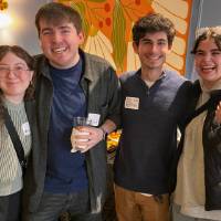 Four alumni smile and hug